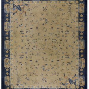 Beige field rug with scattered blue and peach patterns framed by a thick navy blue border.