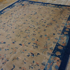 Beige rug featuring scattered blue and peach motifs, bordered in dark navy blue, placed on wood plank floors.