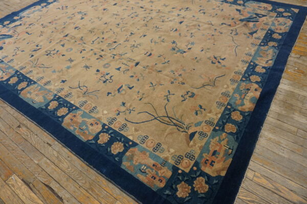 Beige rug with subtle blue and peach patterns and a deep blue ornate border on worn wood floors.