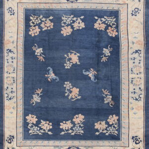 Deep blue rug with pink and light blue floral sprays and a wide cream border of stylized motifs.