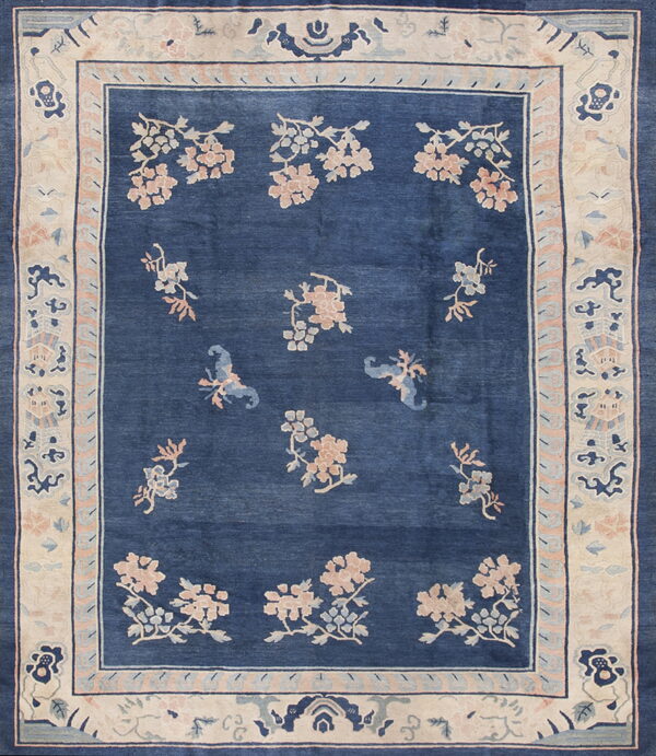 Deep blue rug with pink and light blue floral sprays and a wide cream border of stylized motifs.