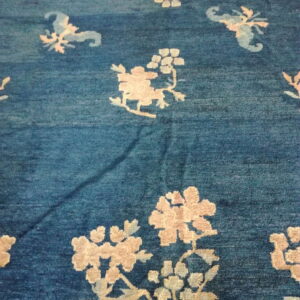 The medium-pile rug features an abrash teal field and scattered large pale botanical motifs.