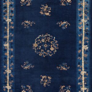 Navy blue rug with tan and light blue borders and scattered floral motifs on wood flooring.