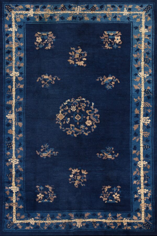 Navy blue rug with tan and light blue borders and scattered floral motifs on wood flooring.