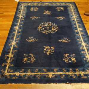 Deep blue rug with scattered gold floral motifs and an elaborate border on wood planks.