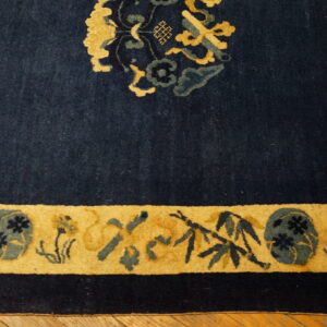 Dark blue high-pile rug featuring gold and teal floral patterns along a thick border on a wood floor.
