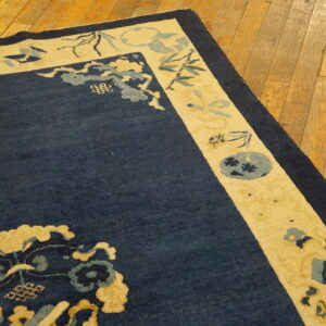 Navy blue rug with a cream patterned border, featuring yellow and light blue accents on wood floors.