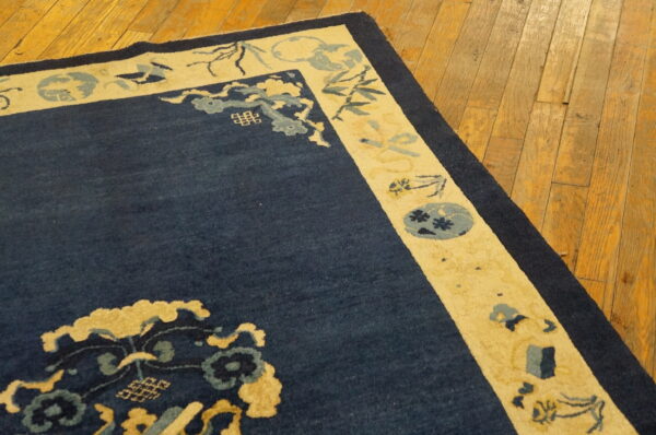 Navy blue rug with a cream patterned border, featuring yellow and light blue accents on wood floors.