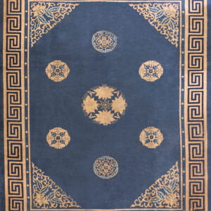 Navy rug with a tan Greek key border and six circular gold floral medallions on a deep blue field.
