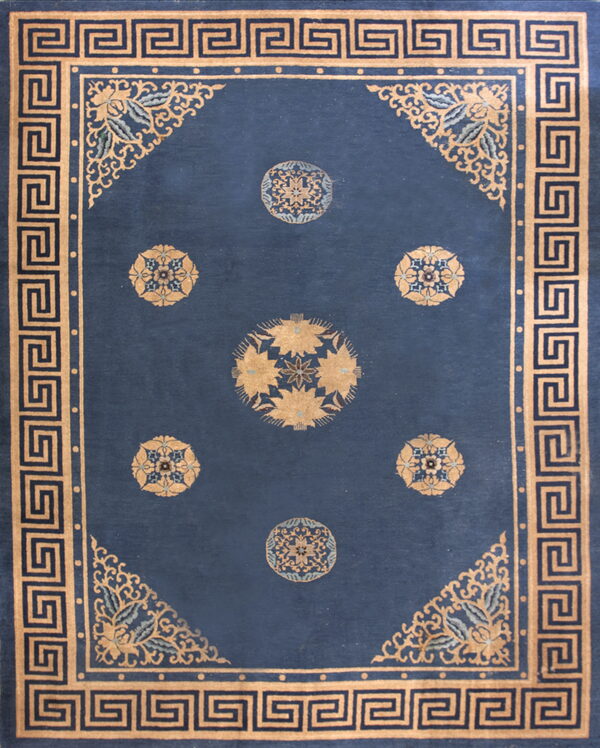 Navy rug with a tan greek key border and six circular gold floral medallions on a deep blue field.
