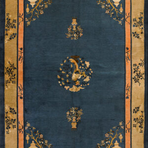 A navy blue rug with gold, pink, and tan borders featuring pagoda and bird motifs on wood floor.