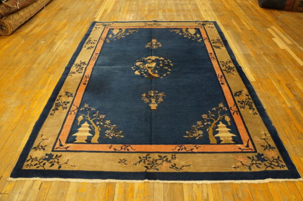 Navy and tan rug displaying asian-style pagodas and birds, set on shiny wood flooring.