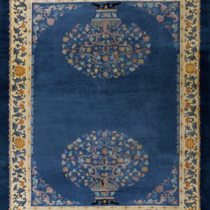 Navy rug with two central flowering vase designs and an ornate tan and blue floral border.