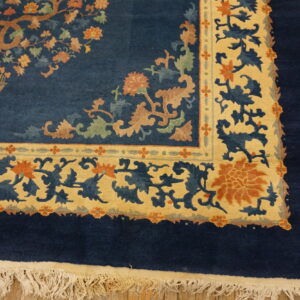Deep blue rug with gold and rust floral borders and a central potted tree design on wood floors.