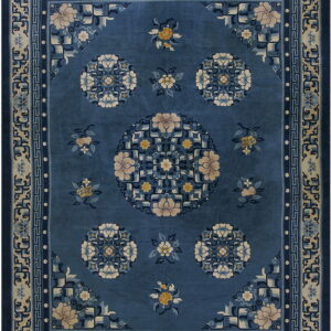 Ornate blue rug featuring a central floral medallion and geometric borders in beige and navy.