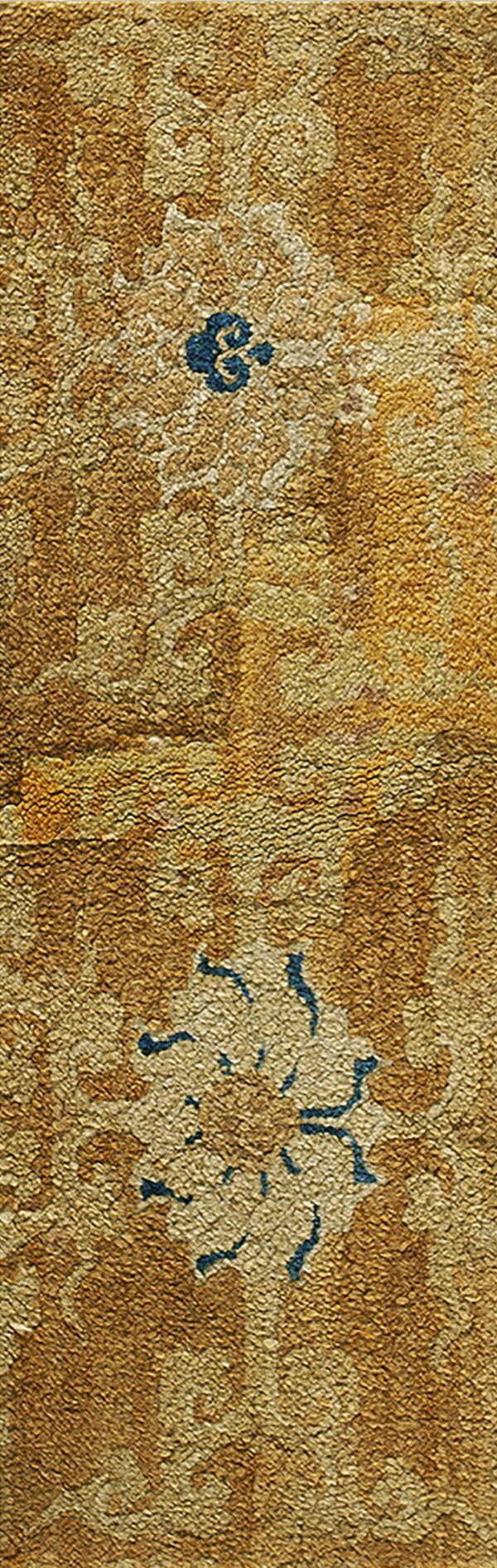 Textured gold rug detail showing large floral motifs and small accents of dark blue.