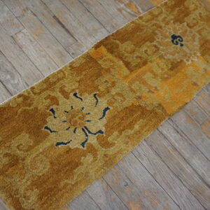 High-pile runner rug in shades of gold and mustard with navy floral accents on weathered wood flooring.