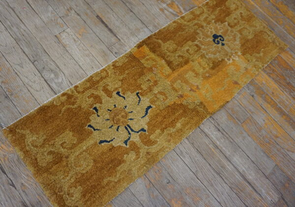 High-pile runner rug in shades of gold and mustard with navy floral accents on weathered wood flooring.