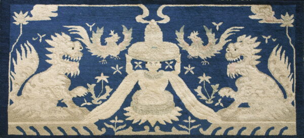 Textured navy blue rug displaying a beige pattern of dragons, flying birds, and a central crowned figure.