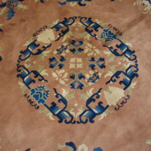 Pinkish-brown rug featuring a detailed central medallion and scattered floral designs in blue, cream, and green.