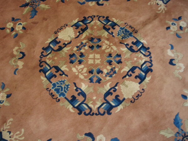Pinkish-brown rug featuring a detailed central medallion and scattered floral designs in blue, cream, and green.