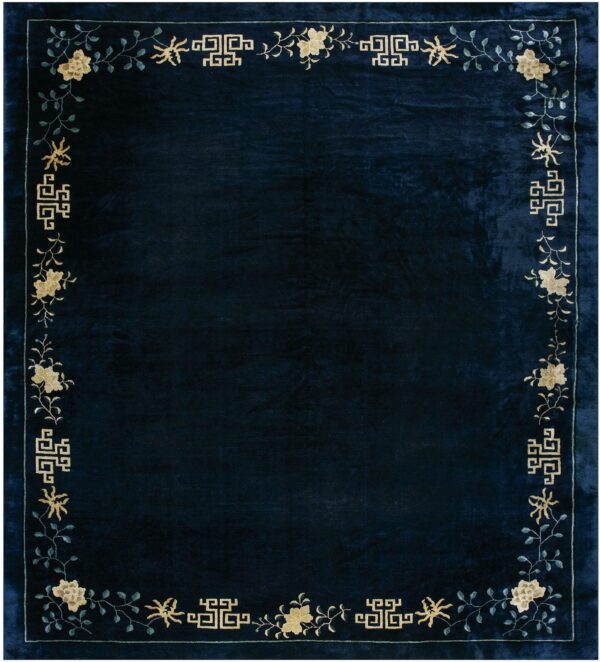 Deep navy rug with a beige floral, vine, and geometric patterned border.