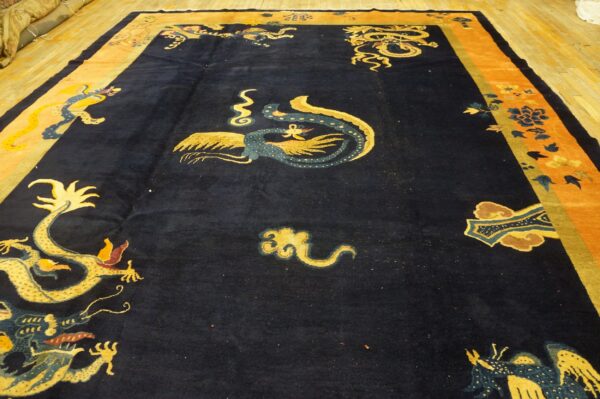 Plush, navy rug with gold dragon motifs and wide orange borders rests on light wood floorboards.