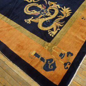 Navy dragon rug with a thick rust orange border and olive accent stripe on hardwood flooring.