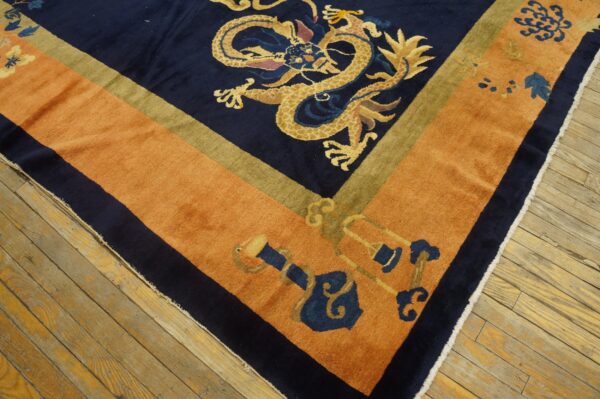 Navy dragon rug with a thick rust orange border and olive accent stripe on hardwood flooring.