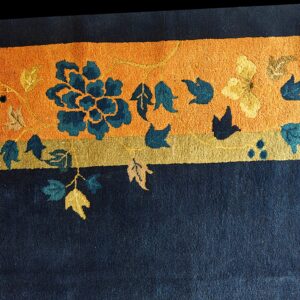 Textured navy rug with a bright orange band featuring teal and yellow stylized floral patterns.