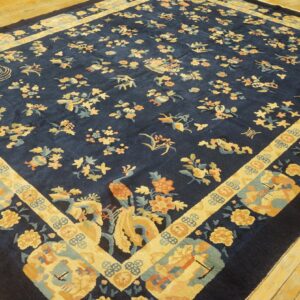 Dark blue rug featuring an ornate pattern of yellow birds and scattered flowers on rustic yellow wood flooring.