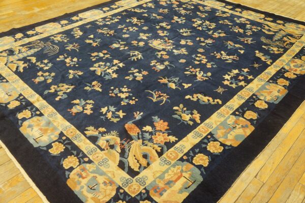 Dark blue rug featuring an ornate pattern of yellow birds and scattered flowers on rustic yellow wood flooring.