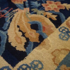Detailed view of a rug with deep blue, light blue, and golden-tan floral and geometric designs.