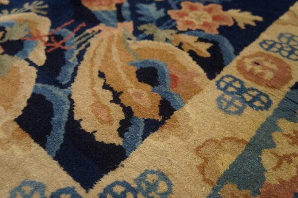Detailed view of a rug with deep blue, light blue, and golden-tan floral and geometric designs.