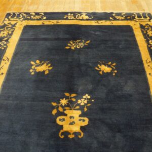 Dark blue rug with contrasting golden-yellow floral borders and central motifs on wood planks.