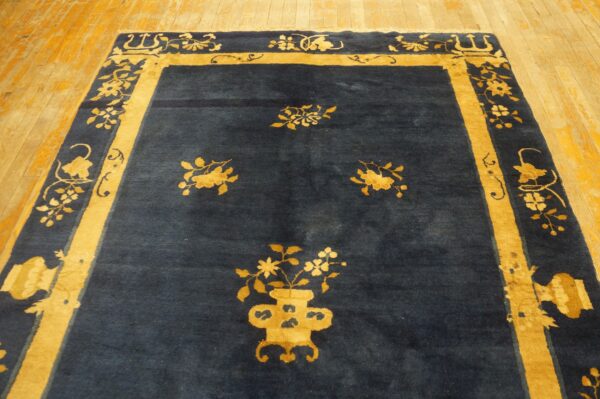 Dark blue rug with contrasting golden-yellow floral borders and central motifs on wood planks.