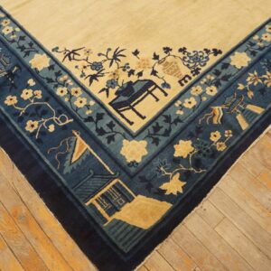 Cream rug with blue and teal borders showing architectural and floral patterns on worn wood planks.