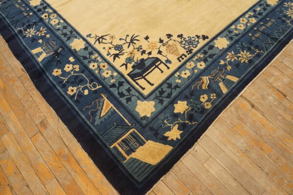 Cream rug with blue and teal borders showing architectural and floral patterns on worn wood planks.