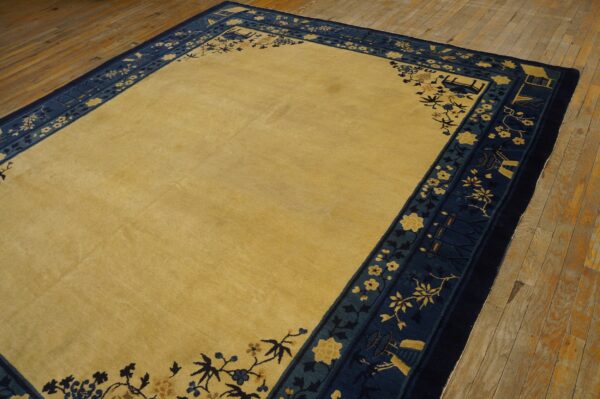 Low-pile rug with a solid gold field and detailed navy and gold floral border on rustic wood planks.