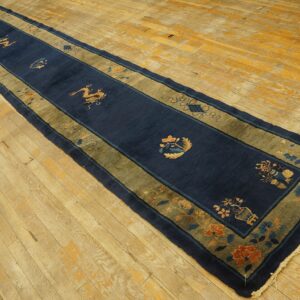 Navy blue Peking runner rug with golden dragon motifs and a wide moss green border on light wood floors.