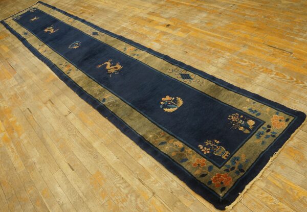 Navy blue peking runner rug with golden dragon motifs and a wide moss green border on light wood floors.