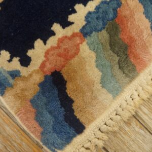 Colorful high-pile rug with abstract patterns and thick knotted fringe resting on light wood flooring.