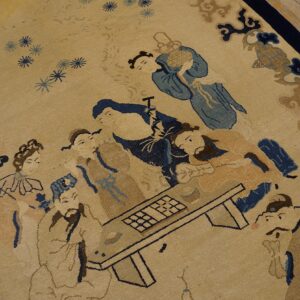 Beige rug with a detailed scene of figures in blue and tan, framed by a dark blue border.