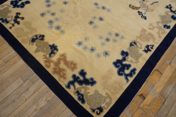 Beige rug with navy border and stylized blue, tan, and terracotta cloud patterns on wood floors.