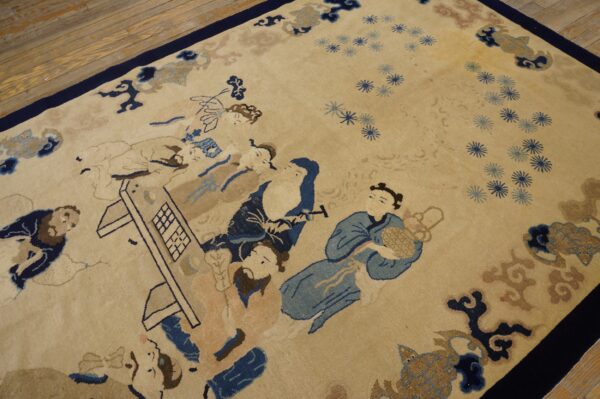 Beige rug with navy, blue, and tan figural pattern resting on light hardwood floors.