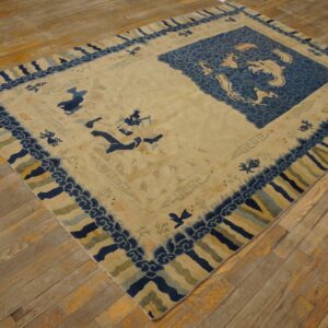 Beige and blue rug featuring a central dragon motif and patterned borders resting on wood plank flooring.