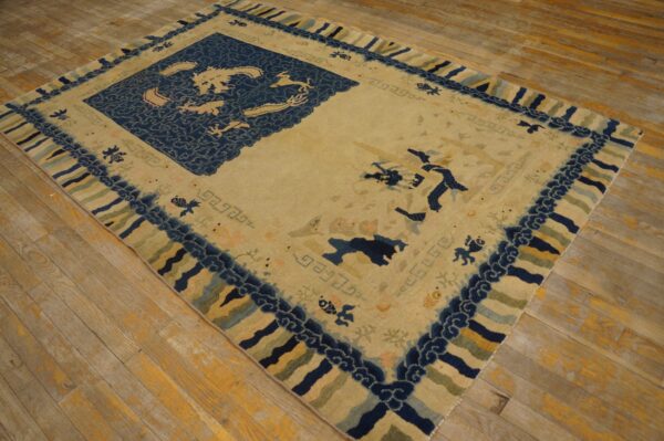 Cream and indigo rug with mythological animal motifs and striped borders rests on weathered wood planks.