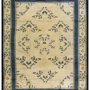 Light gold rug with navy blue geometric Greek key borders and scattered floral designs.
