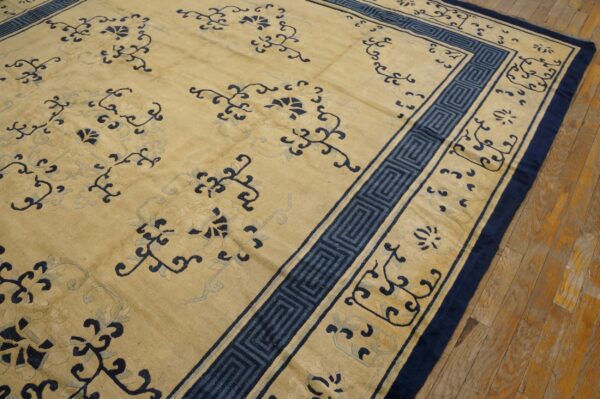 Pale yellow rug with deep blue meandering border and scrolling floral patterns on wood planks.