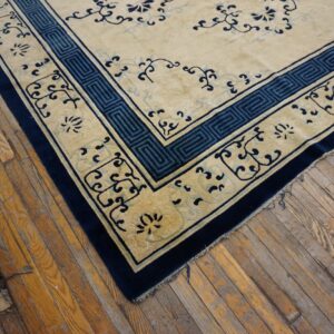 Beige rug with navy and light blue patterns and geometric borders sits on rustic wooden floorboards.